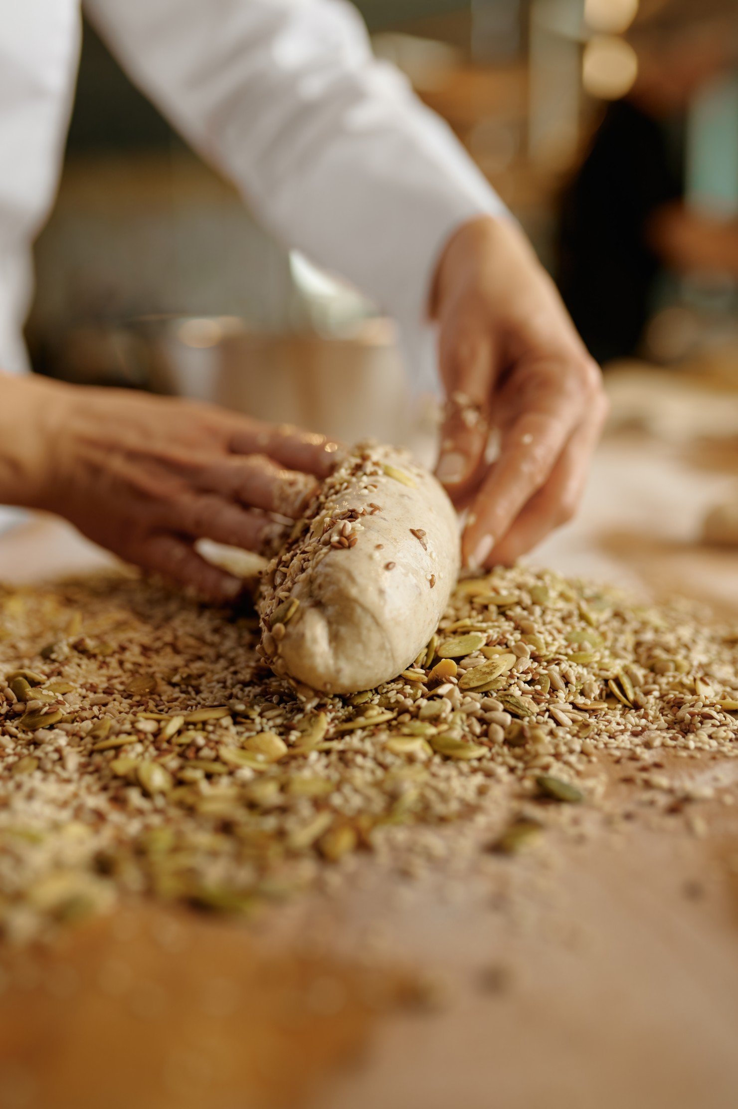 Panadero dando forma a los bagels, untando la masa con semillas y copos de avena