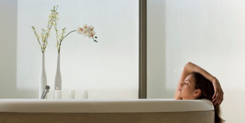 Mujer relajándose en una bañera con vista a la naturaleza, simbolizando el placer propio y la masturbación como parte del autocuidado en la menopausia.