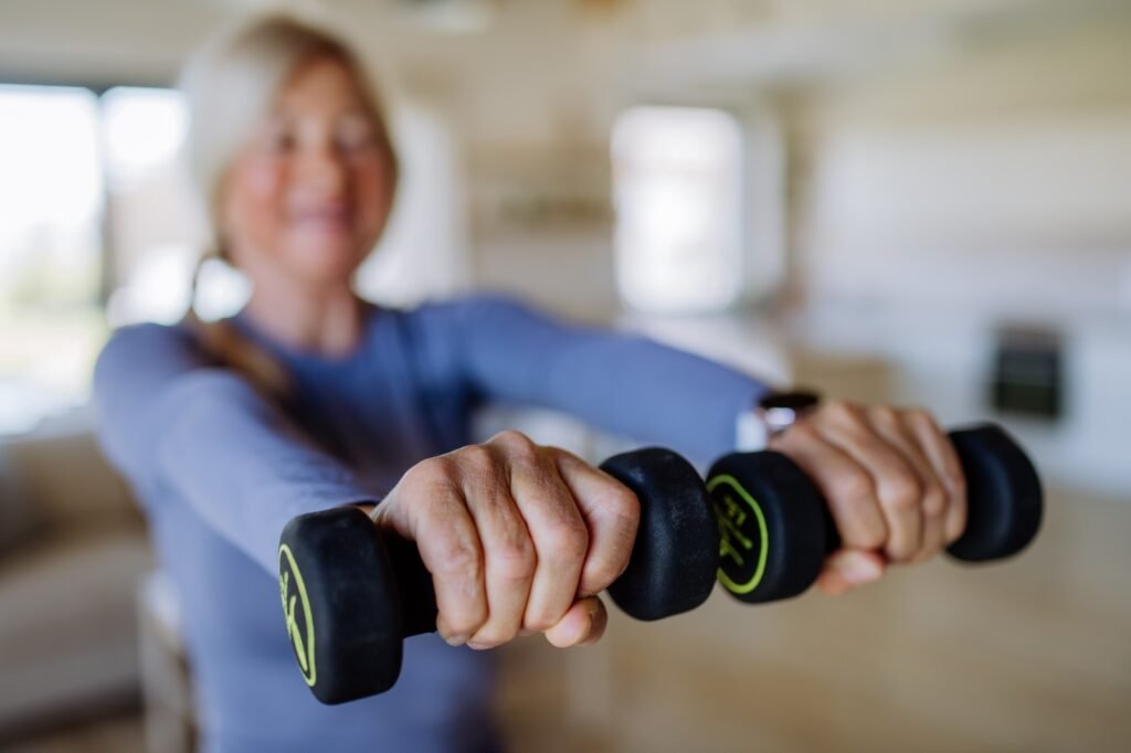 Mujer realizando ejercicios para la menopausia con pesas en casa para mejorar la masa muscular.